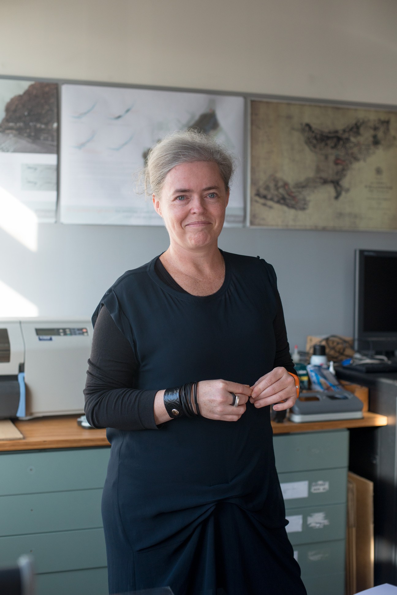 Nicole Thompson of Wraight + Associates standing in an office with architectural drawings on the wall behind her.