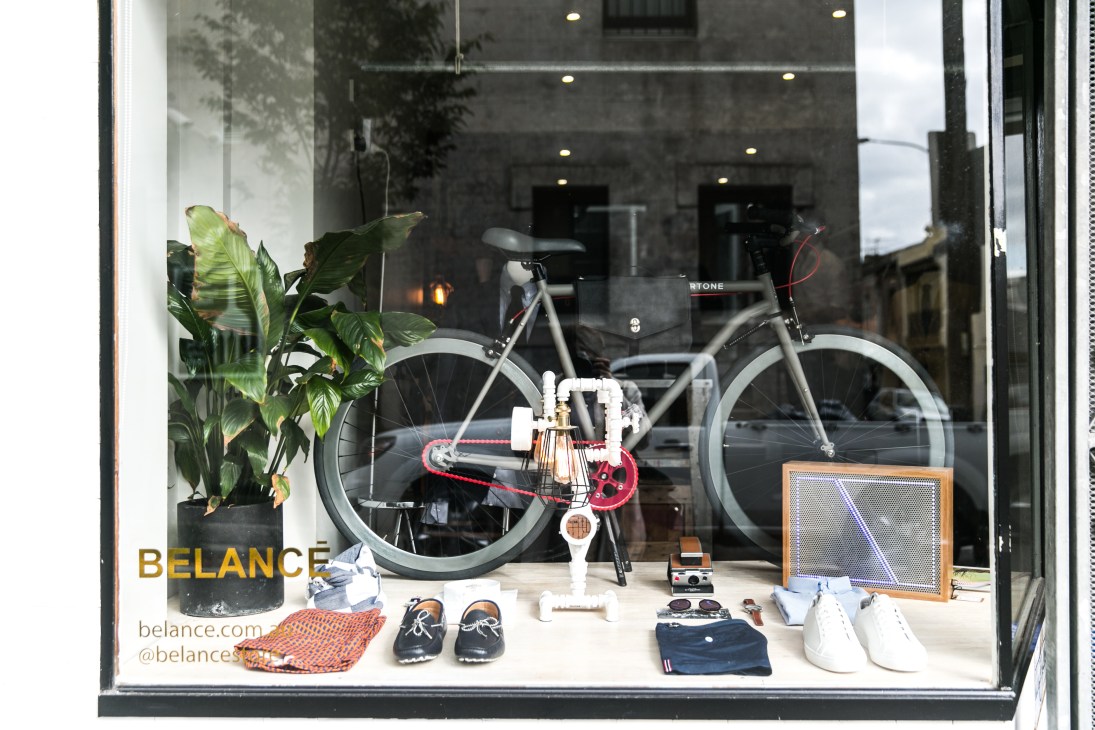 Belancé storefront window displaying a bicycle, shoes, accessories, and plants with the Belancé logo visible.