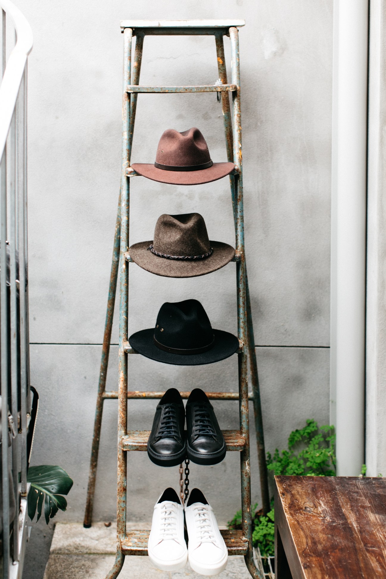Vintage ladder displaying hats and shoes in ascending order on white wall