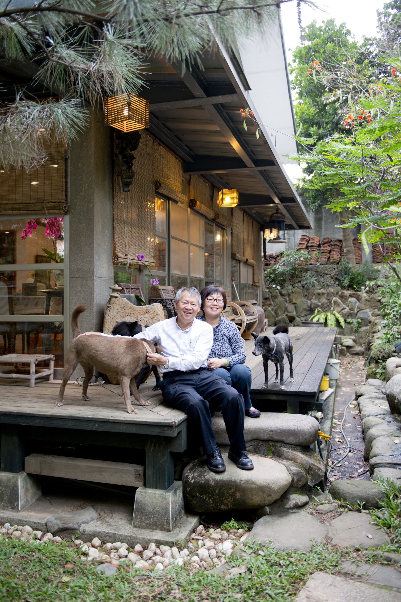 Architect Wu Wen-Chung and his wife Wu Chen Ming-Jun sit on a wooden deck with their dogs in front of their restored century-old Beitou home.