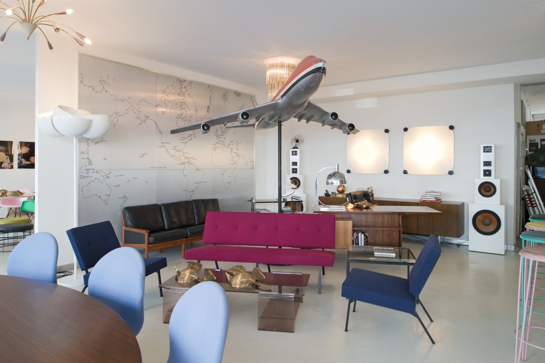 Vintage-furniture shop Elastique interior with mid-century seating and a suspended aircraft model.