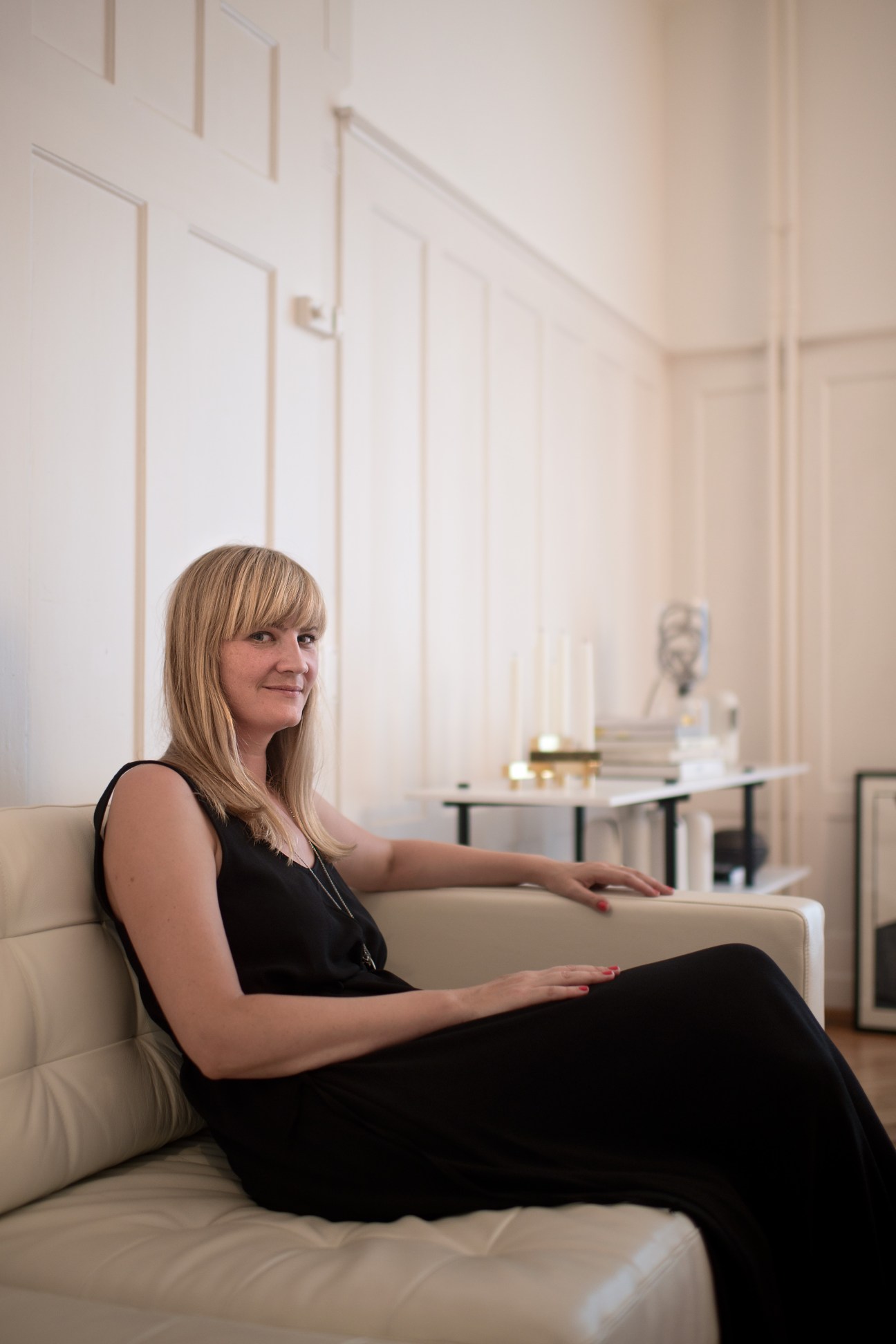 Product designer Isabell Gatzen sitting on a white sofa in her minimalist apartment in Zürich's Kreis 4.