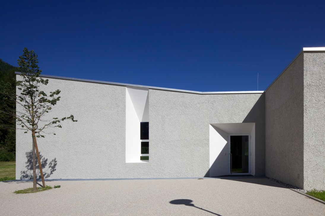 Contemporary white fire station with recessed windows and sharp angles in South Tyrol.