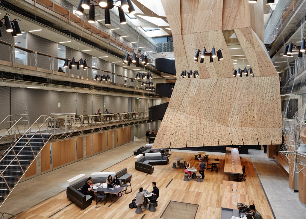 Students work across multiple floors in the main atrium of the Melbourne School of Design with suspended timber studios overhead.