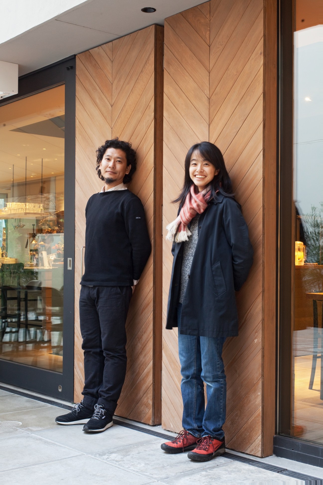 Masahiro and Mao Harada of Mount Fuji Architects Studio stand outside the Three Aoyama storefront with hinoki wood doors in herringbone pattern.
