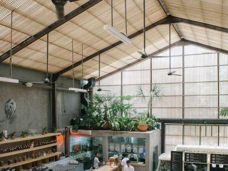 Overhead view of Three Buns restaurant in Jakarta with counter seating, plants, and industrial ceiling design.