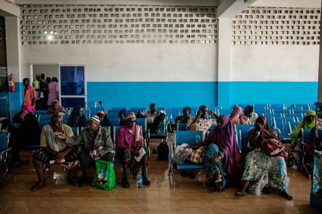 Passengers sitting on blue chairs in a departure lounge at Aden Abdulle International Airport in Mogadishu.