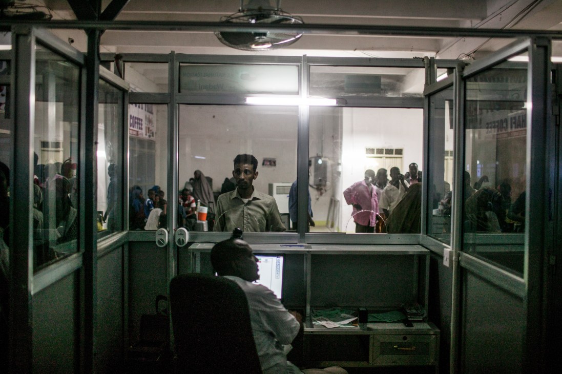 A Somali man waits at an immigration counter behind glass partitions at Aden Abdulle International Airport.