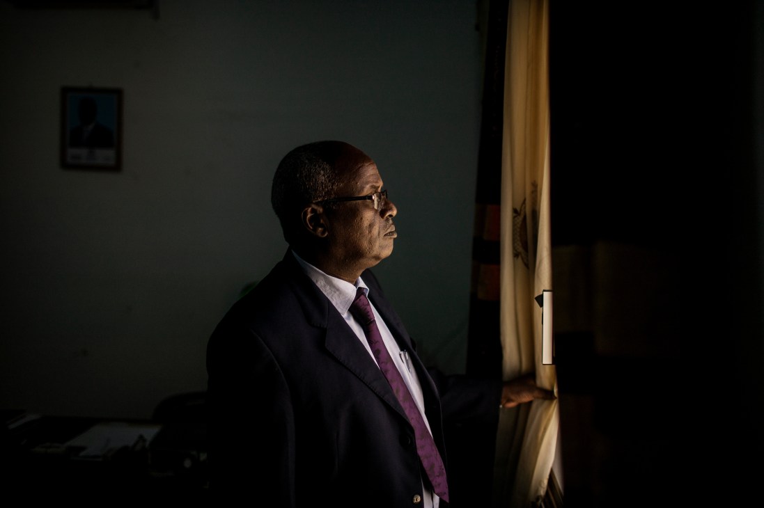Ali Mohamoud Ibrahim, general manager of Somali Civil Aviation and Meteorology Authority, stands in profile wearing glasses and a dark suit with burgundy tie.