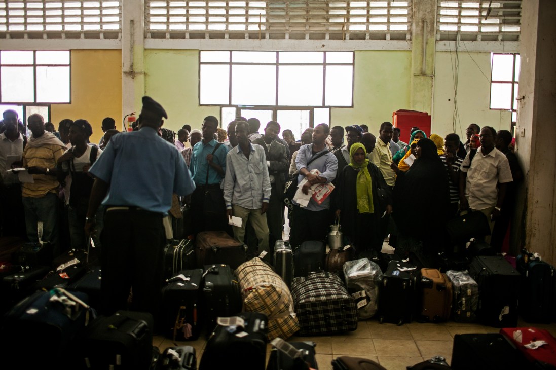Crowded airport terminal with passengers and luggage during morning rush at Mogadishu's Aden Abdulle International Airport.