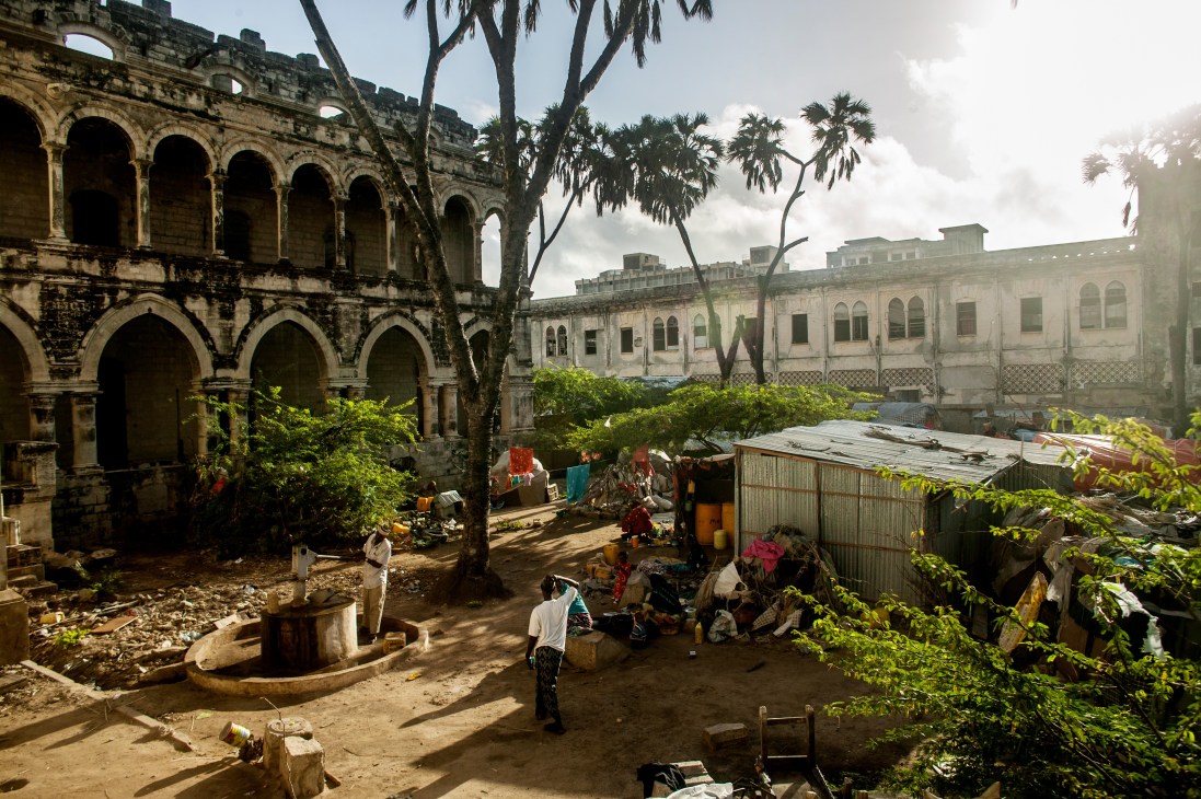 Internally displaced Somalis sheltering in a downtown encampment among ruined colonial buildings and makeshift structures.