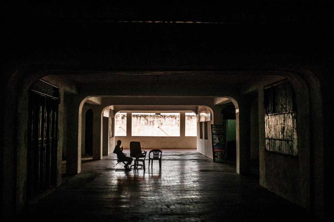 A vendor sits alone in a sparsely furnished newly-built Mogadishu mall with chairs and concrete floors.