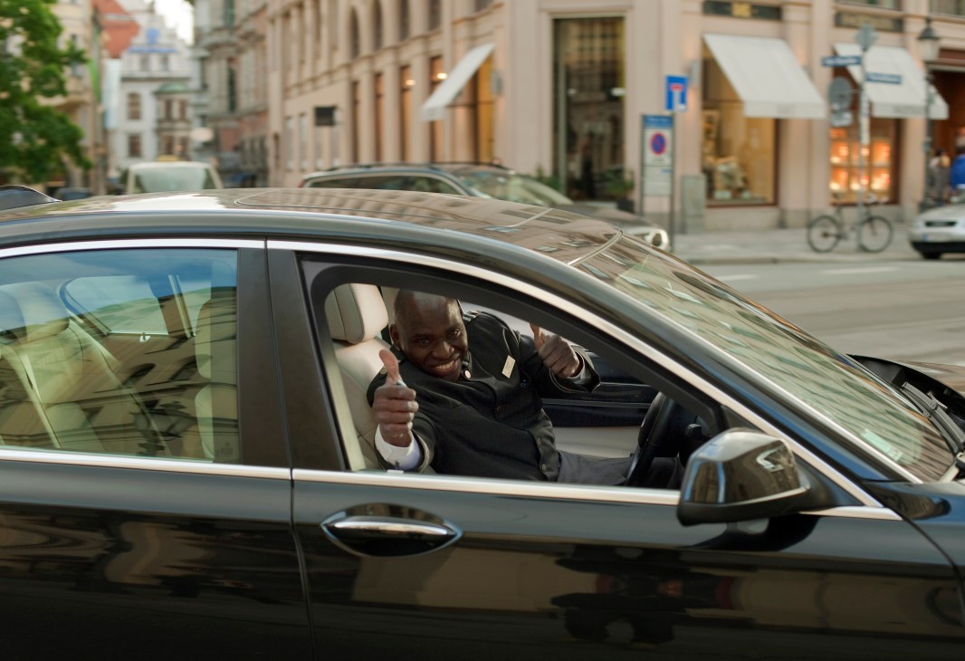 Man giving thumbs up from car window on Munich street
