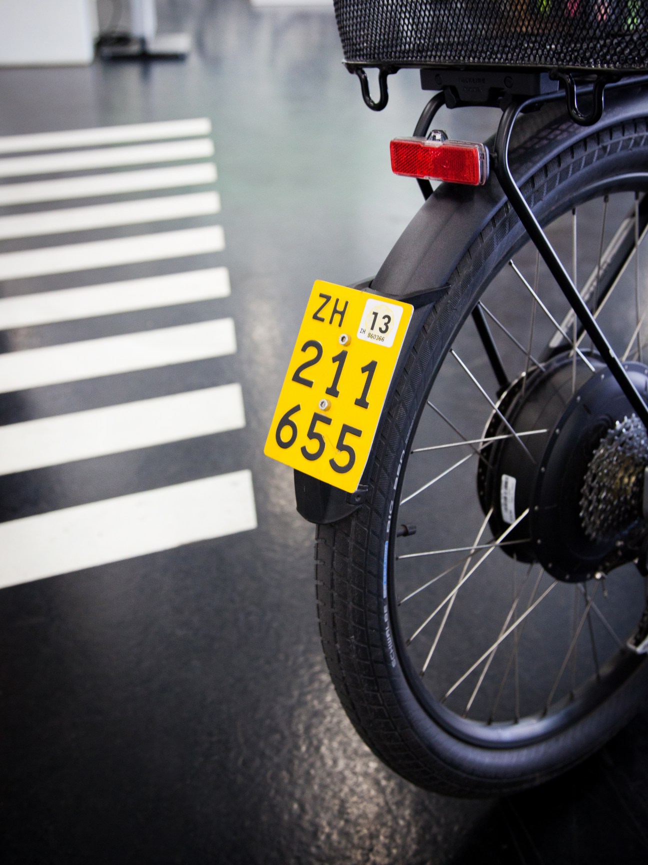 Close-up of an electric bike with a yellow Swiss registration plate showing the number ZH 211 655.