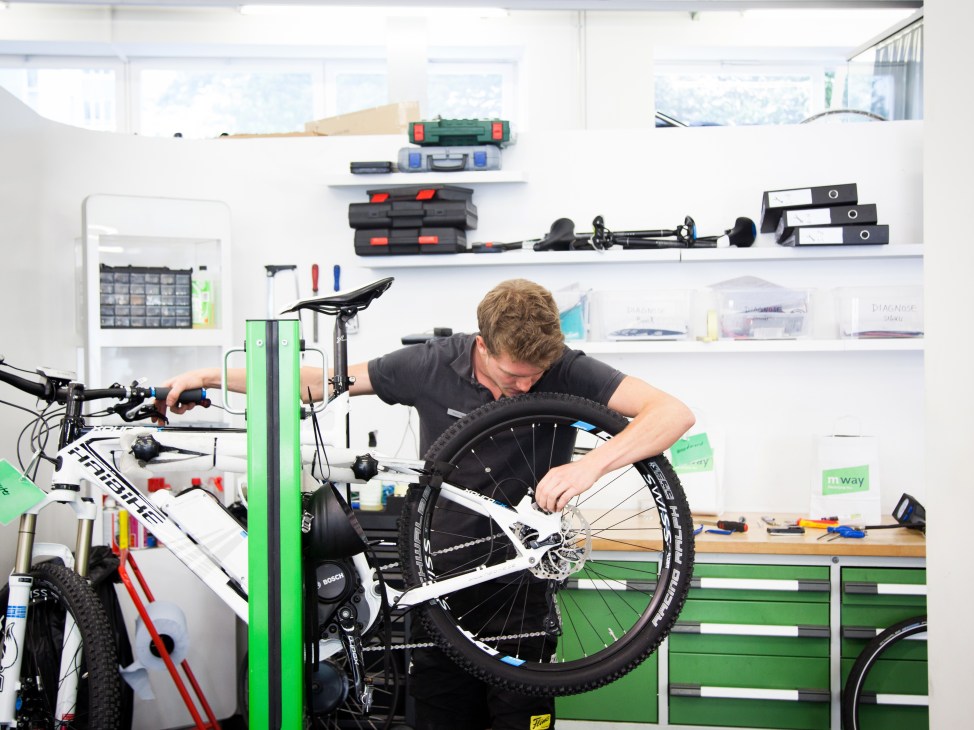 Technician repairs an electric bike wheel at M-way shop in Zürich.