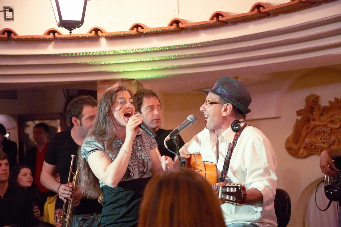 Musicians performing at Anema e Core nightclub on Capri, with a woman singing and a man playing guitar under an ornate ceiling.