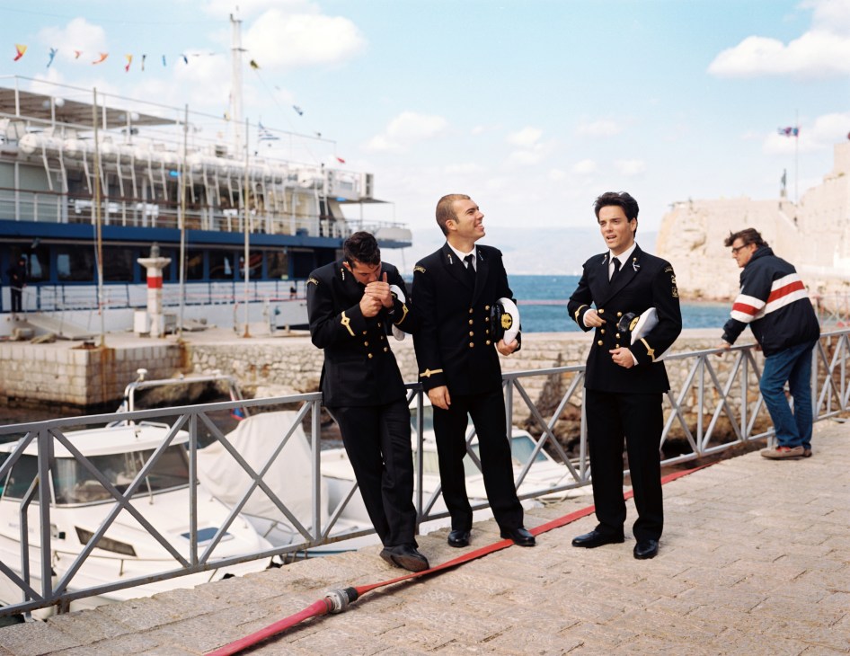 Naval academy students in dress uniforms relax at a Greek harbour after a parade ceremony.
