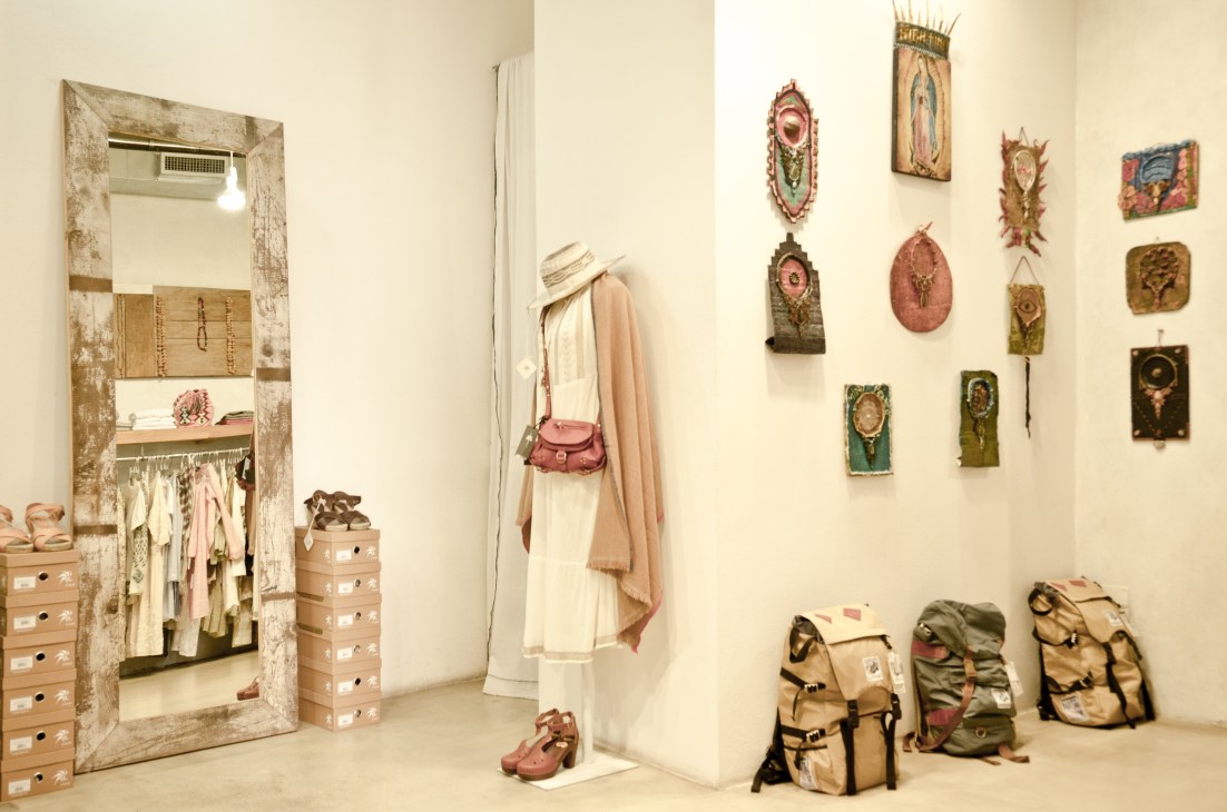 Made in the Shade boutique interior in Milan featuring vintage-style décor, clothing on display, decorative wall art, and canvas backpacks.