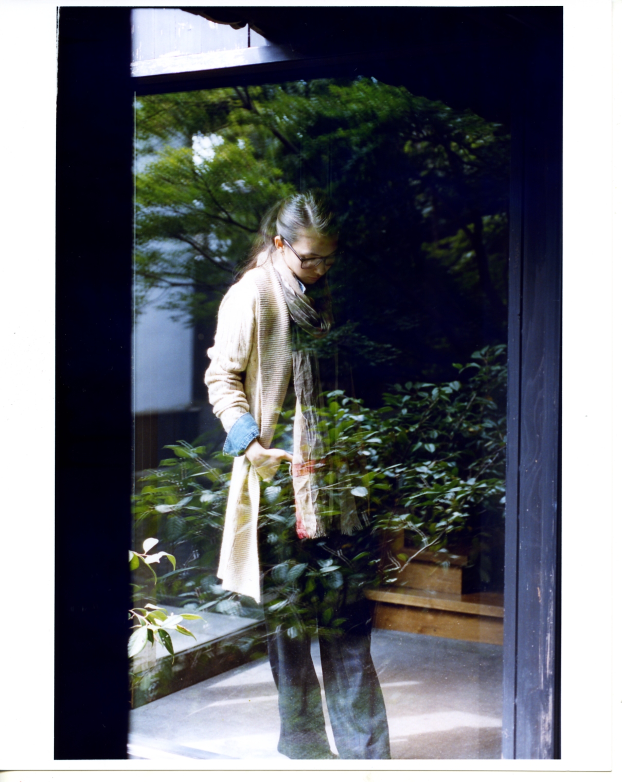 Model wearing Ralph Lauren Blue Label cardigan and Drawer trousers stands in doorway overlooking lush garden in Obuse.