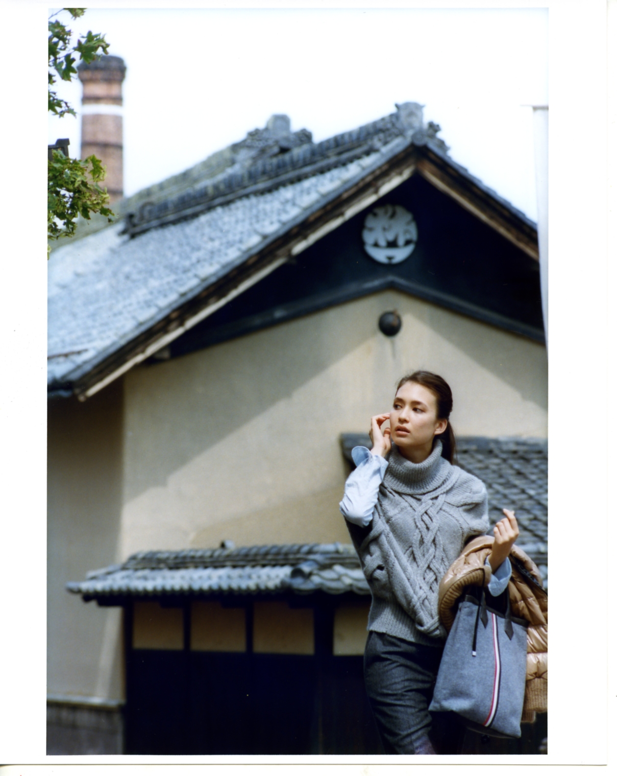 Model wearing Gucci poncho and Beams shirt posed against traditional Japanese architecture in Obuse.