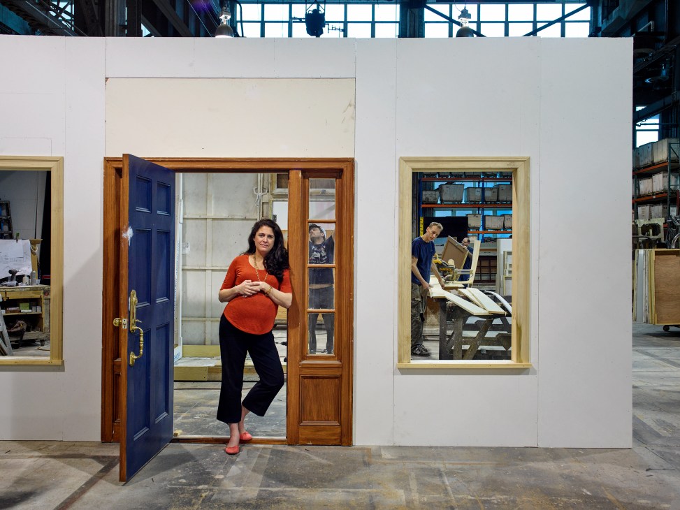 Nicole Stiegelbauer, nine months pregnant, stands in a doorway of a set piece in the Brooklyn Navy Yard workshop.