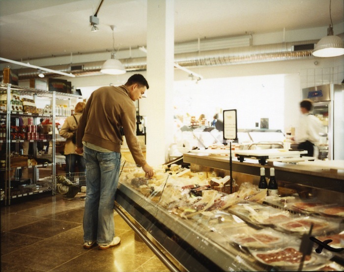 Customer browsing cured meats and products at a deli counter inside Nimb.