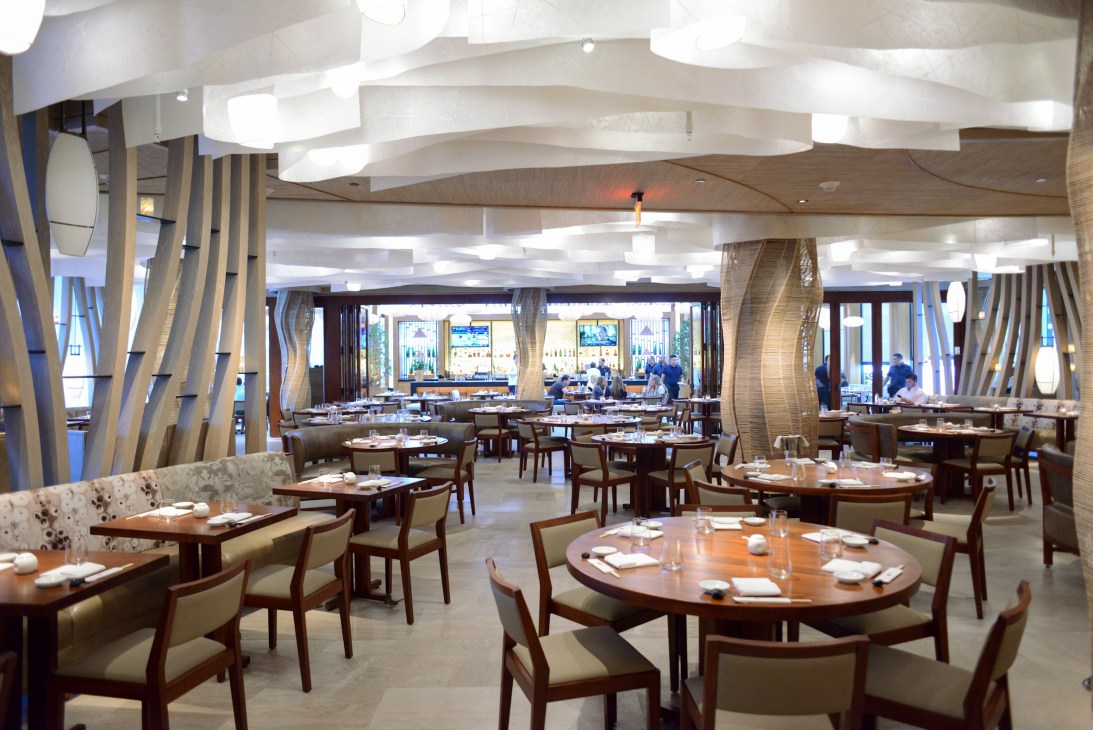 Modern fine dining restaurant interior with round tables, wood chairs, and contemporary lighting fixtures.