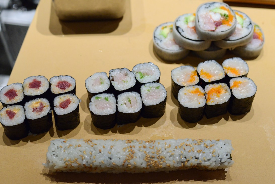 Assorted sushi rolls and nigiri on a pale yellow counter at Nobu restaurant.