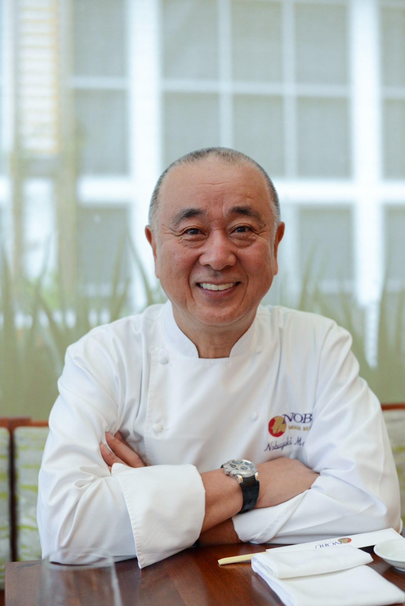 Nobu Matsuhisa smiling at his Miami Beach restaurant in white chef's coat