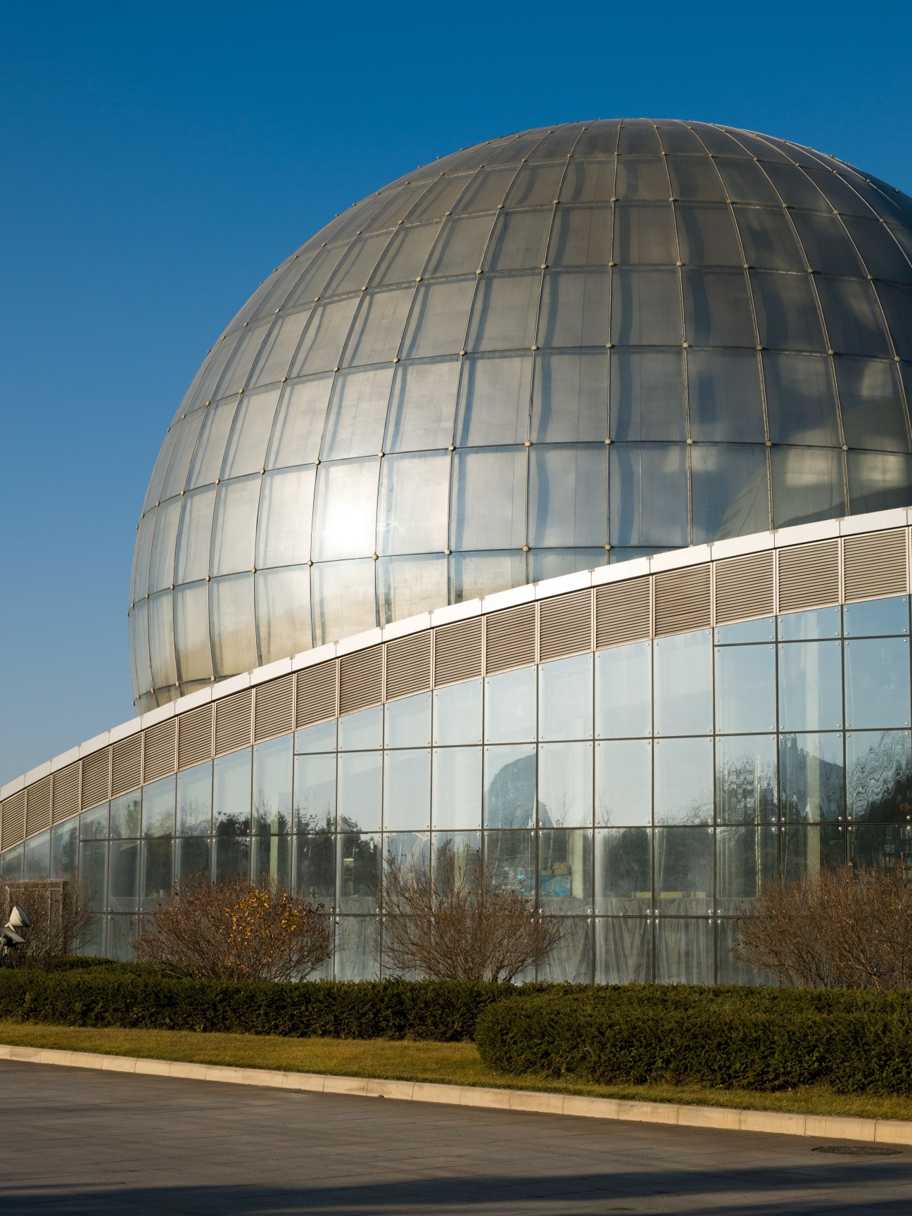 Heilongjiang Science and Technology Museum with spherical glass dome against blue sky.