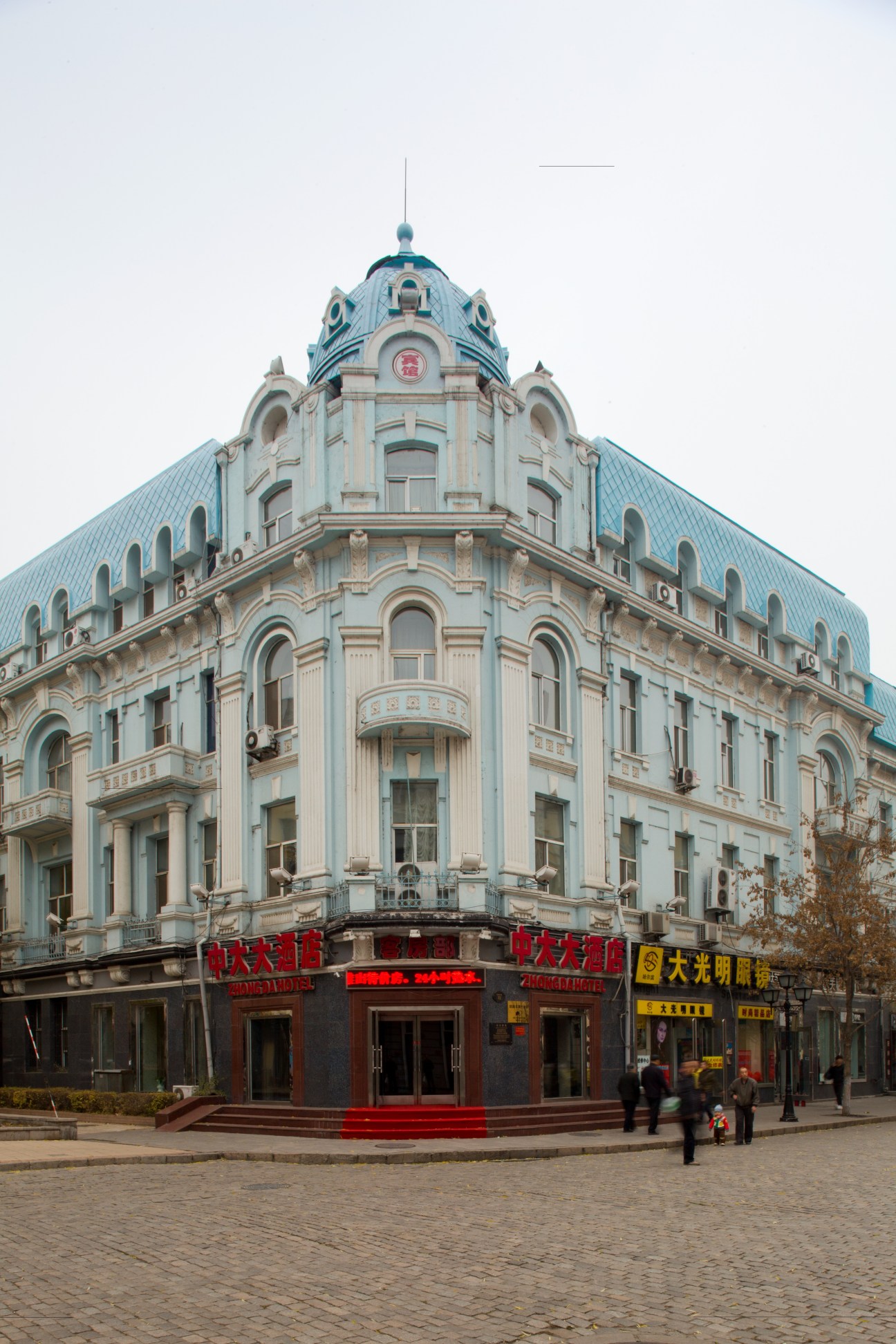 Historic Zhong Da Hotel, a pale blue and cream ornate building with a domed turret and Chinese signage on the ground floor.