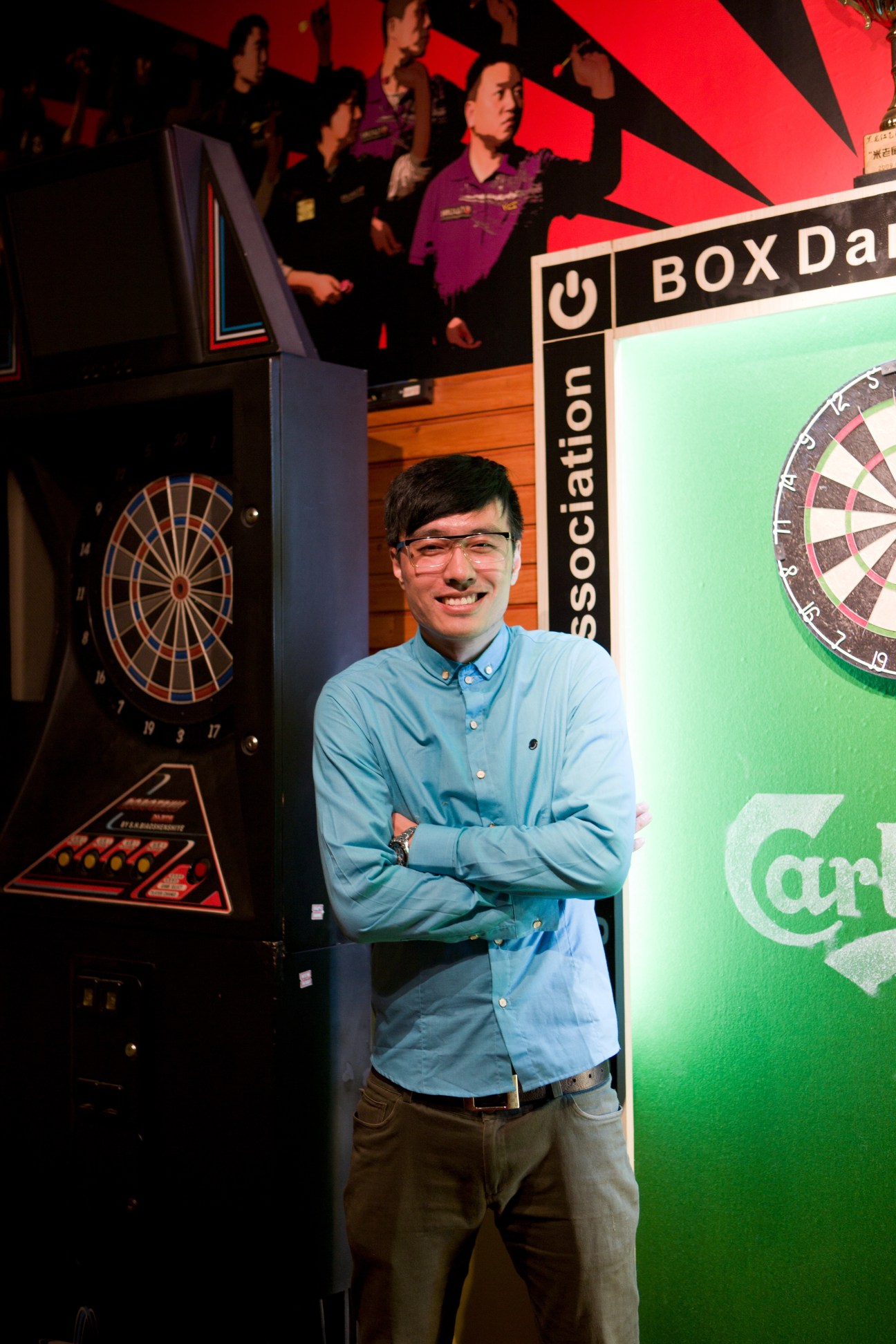 Hip-hop dance instructor Xiao Tian stands with arms crossed in the darts room at Box Town Harbin.