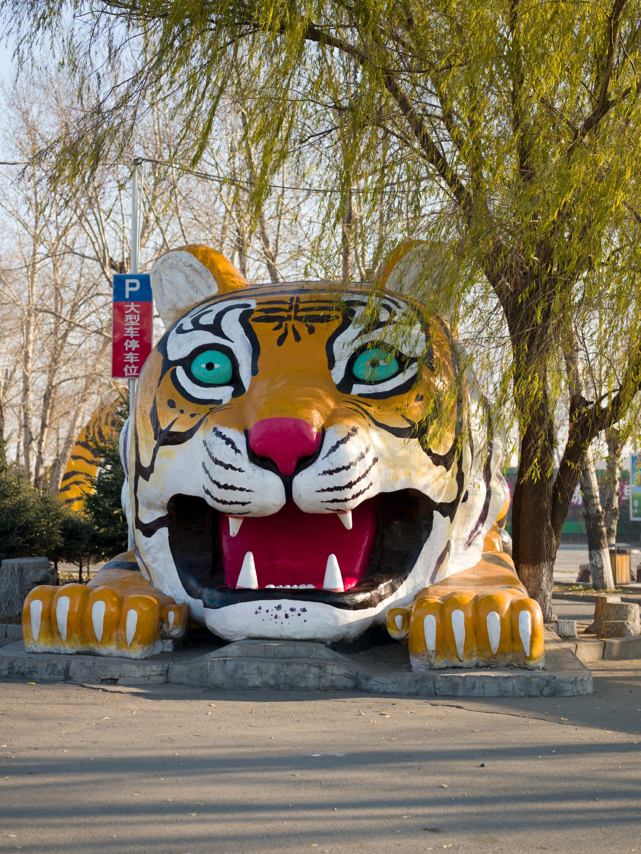 Colorful oversized tiger head sculpture with turquoise eyes and open mouth at Northeast Siberian Tiger Sanctuary entrance.