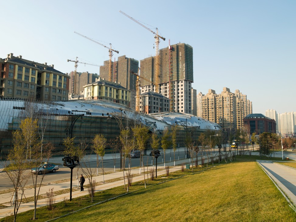 Construction cranes tower over partly completed apartment buildings in Harbin's Qunli New District development.