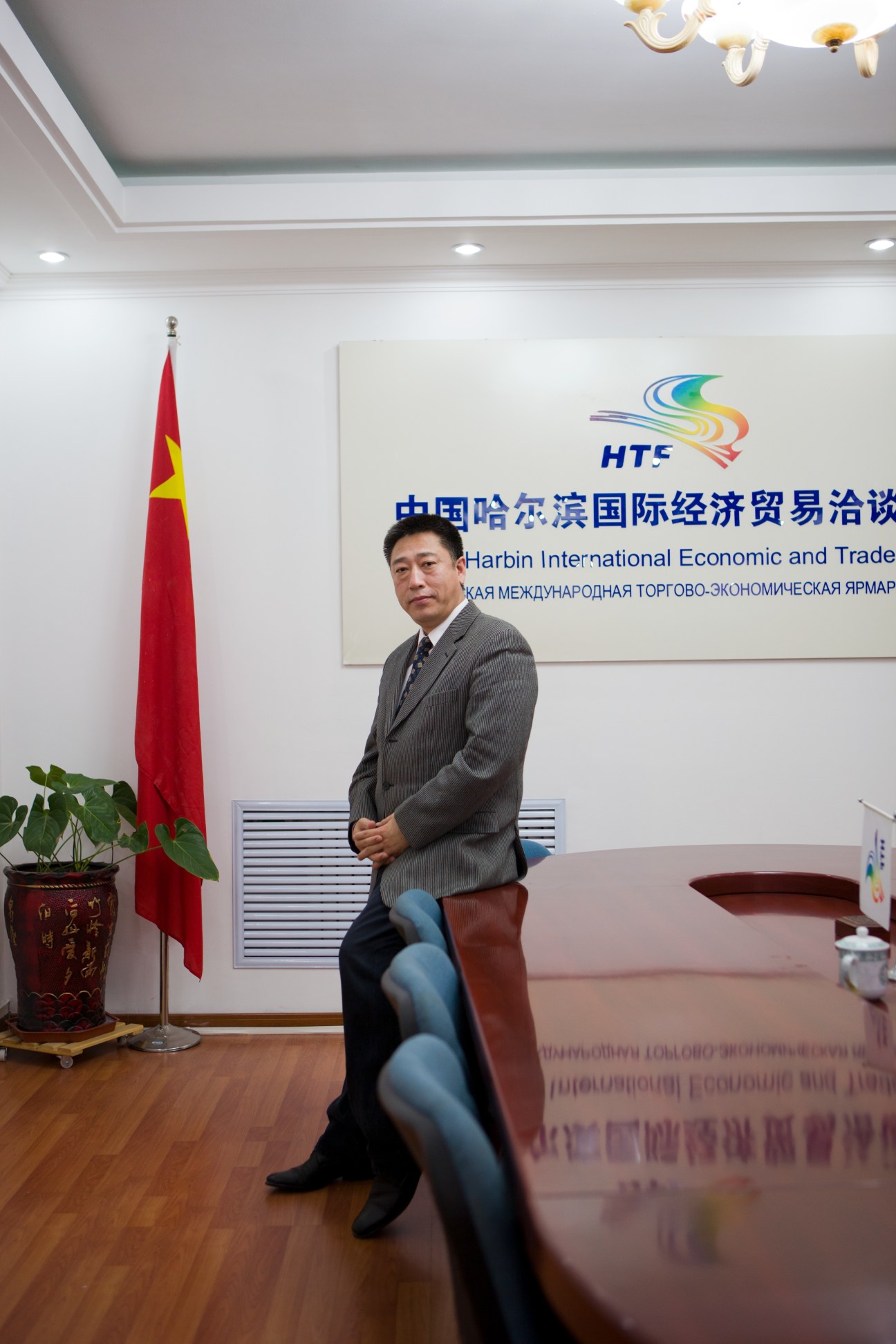 Guan Haibin, Harbin Trade Fair deputy director general, seated in an office with Chinese flag and signage behind him.