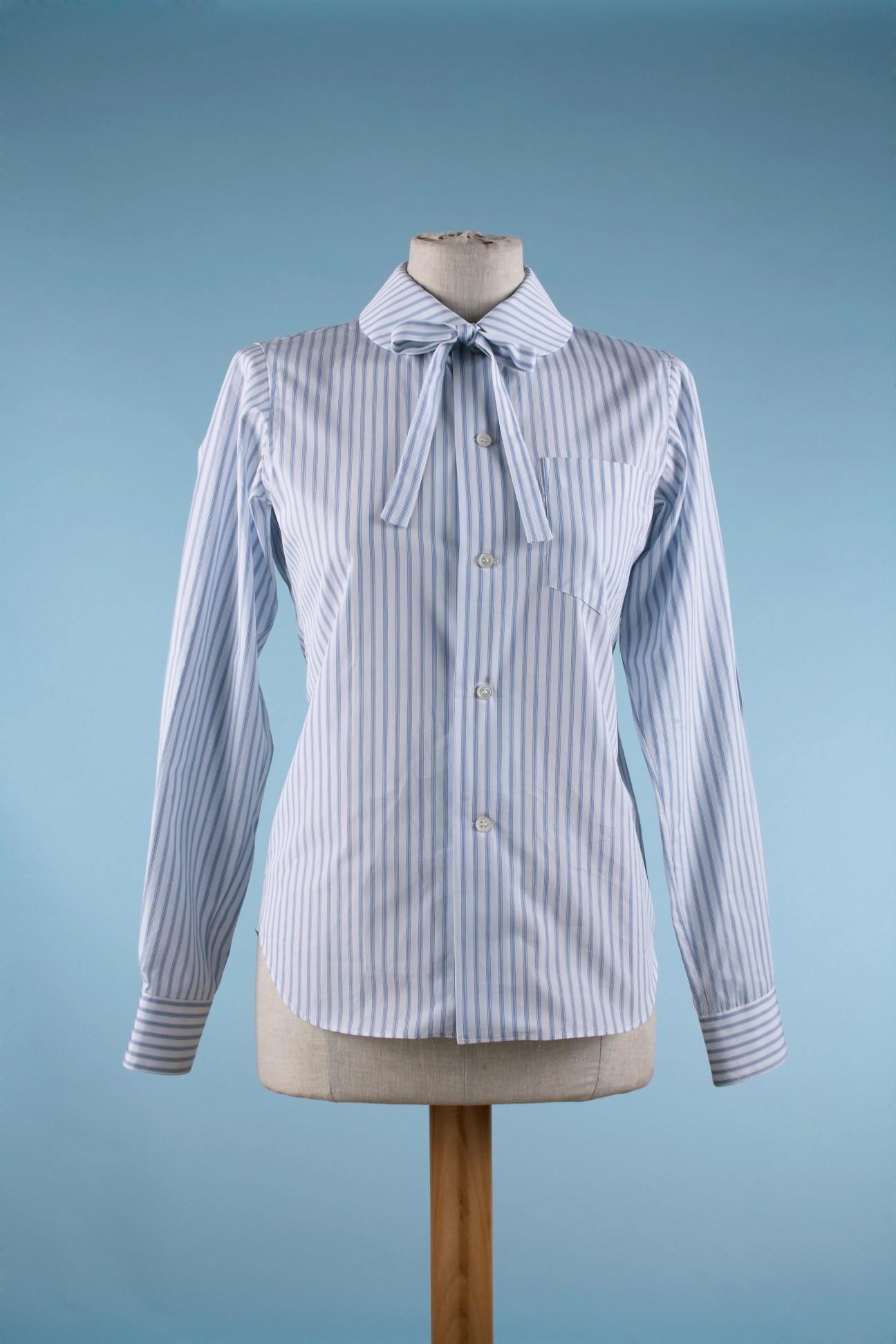 Comme des Garçons women's shirt in blue and white stripes with pussy bow collar detail on dress form.