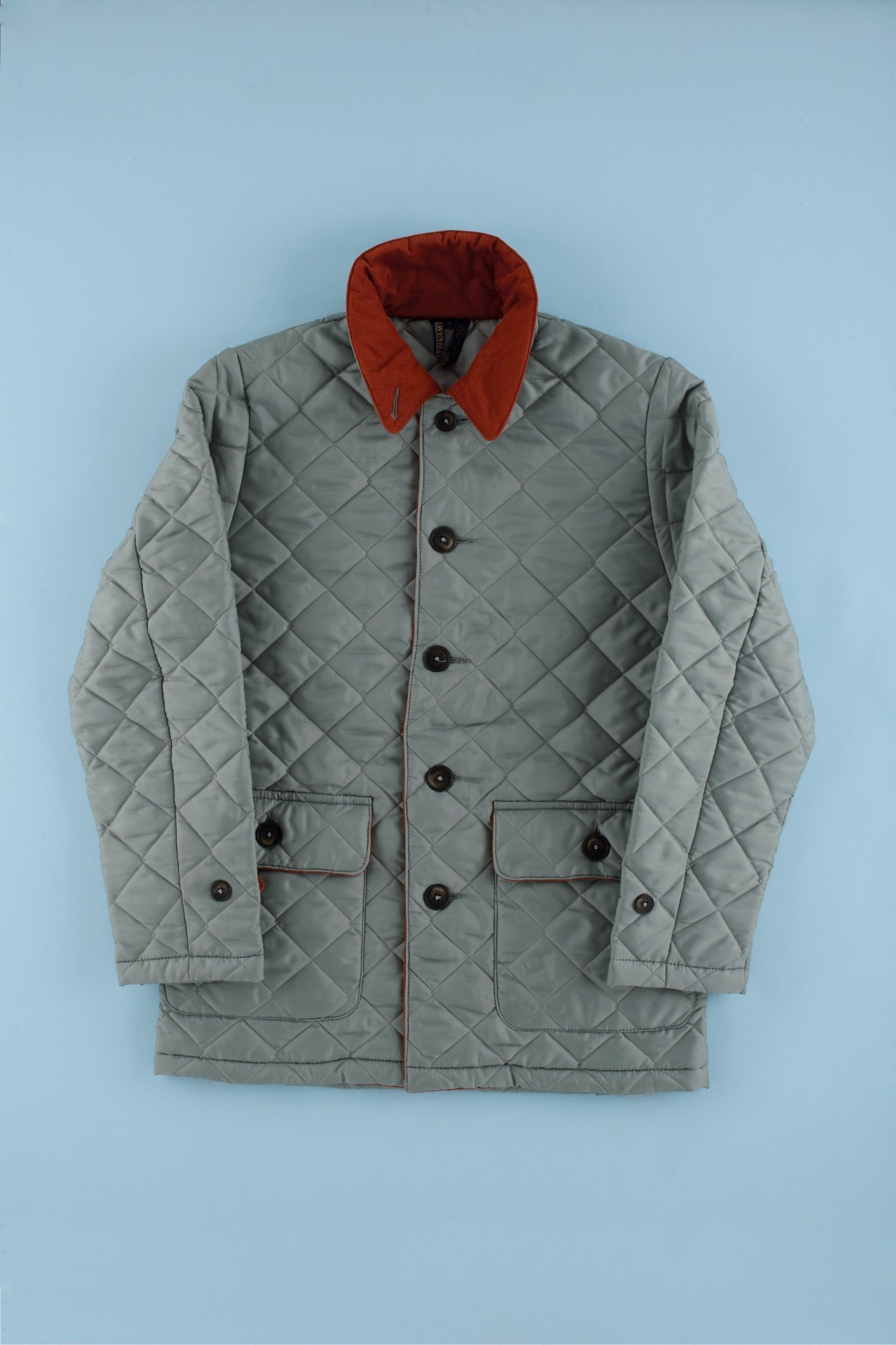 Lavenham quilted jacket with gray exterior, red collar and lining, displayed on light blue background.