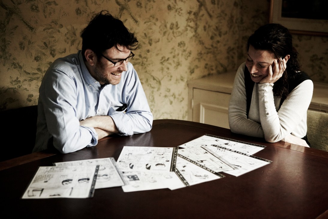 SelfMadeHero founder Emma Hayley and illustrator Glyn Dillon review graphic novel artwork at a table.