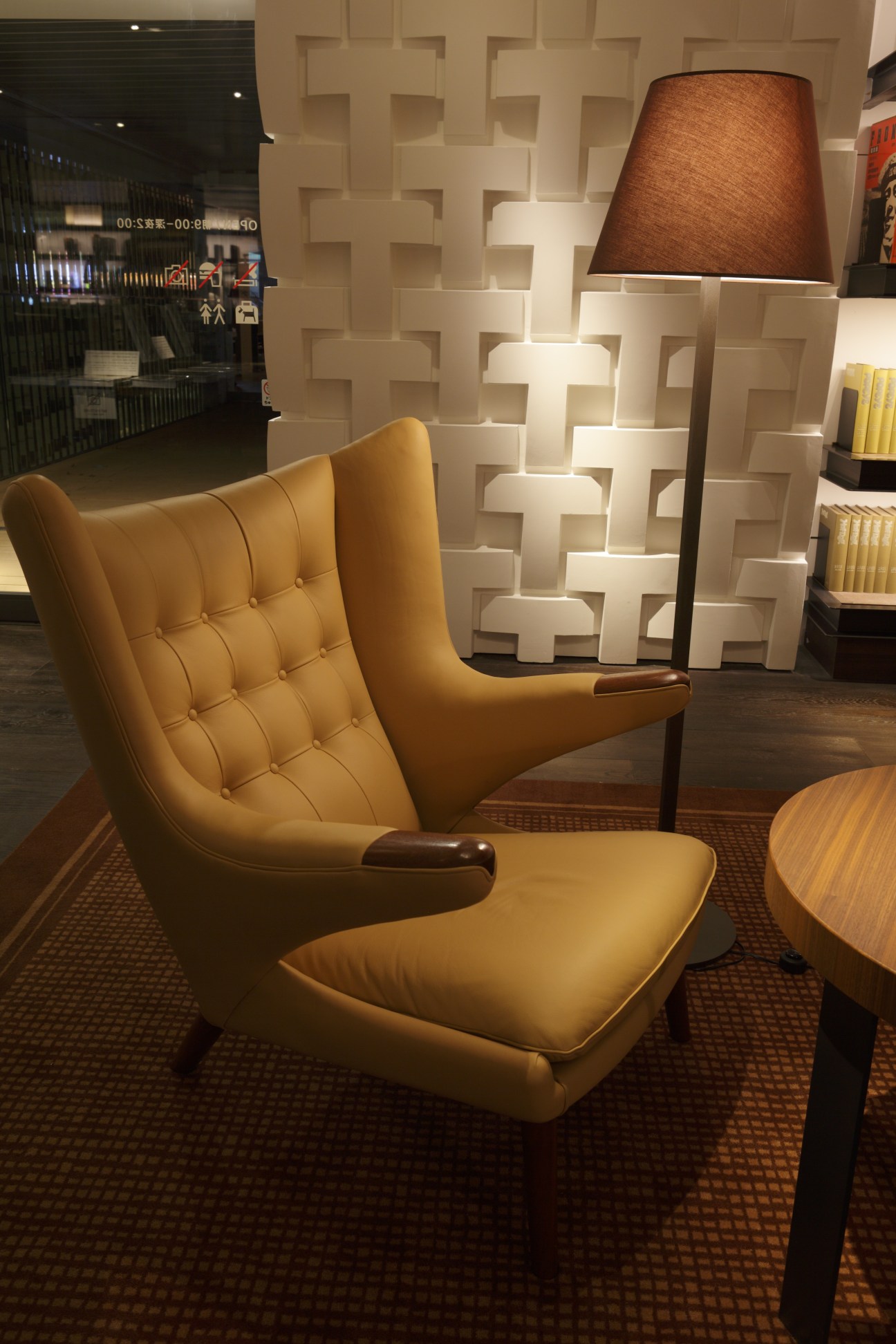 Yellow leather armchair with ottoman in Tsutaya Books' Anjin lounge, with geometric wall pattern and floor lamp.