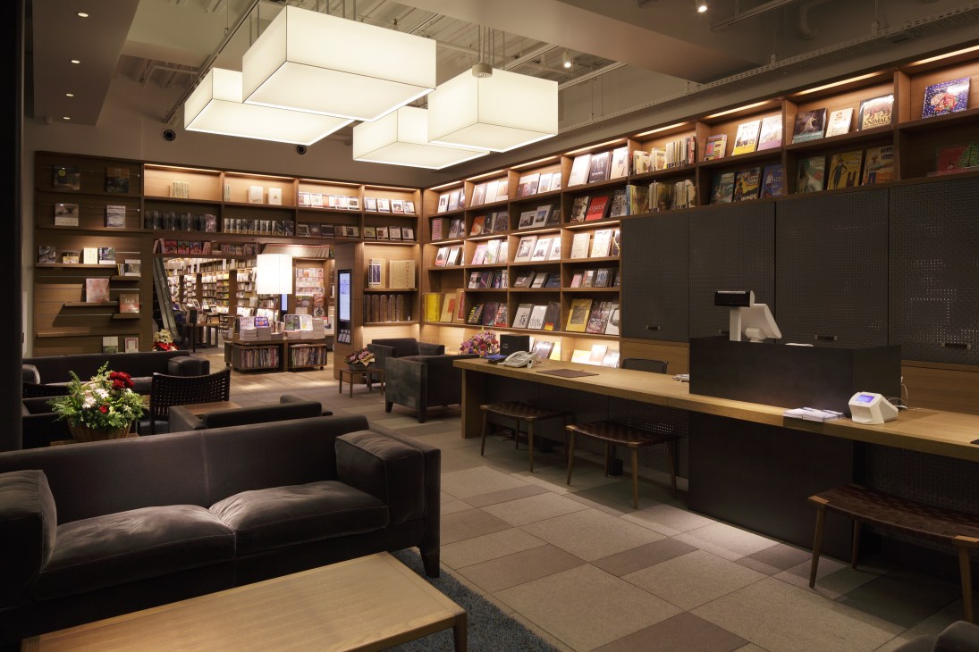 Tsutaya Books concierge desk with wooden shelving, seating areas, and modern lighting in the Tokyo Daikanyama store.