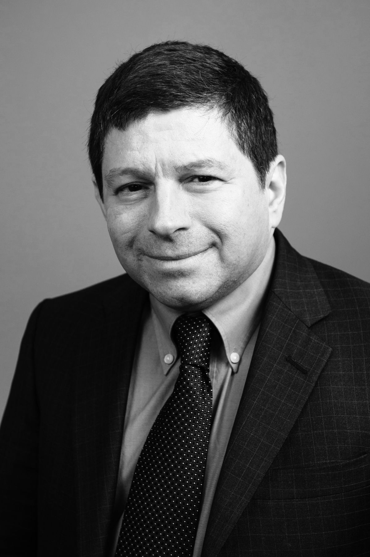 Black and white portrait of Steve Novick, Portland city commissioner, wearing a dark suit and dotted tie.