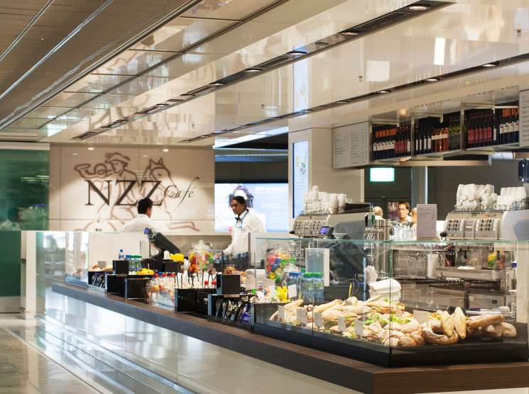 NZZ Café at Zürich airport with counter service, staff, and branded signage in modern terminal setting.