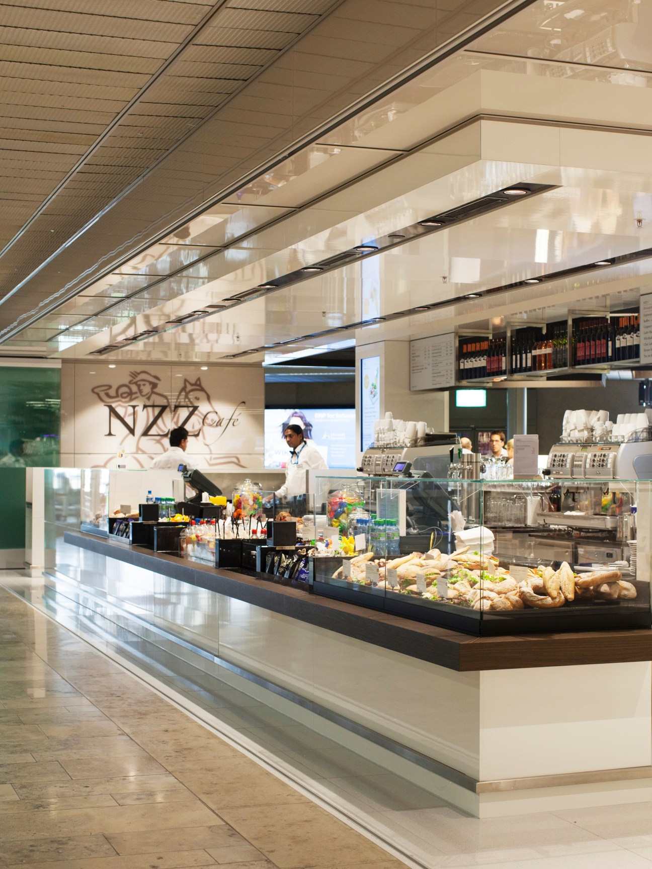 NZZ Café at Zürich airport with counter service, staff, and branded signage in modern terminal setting.