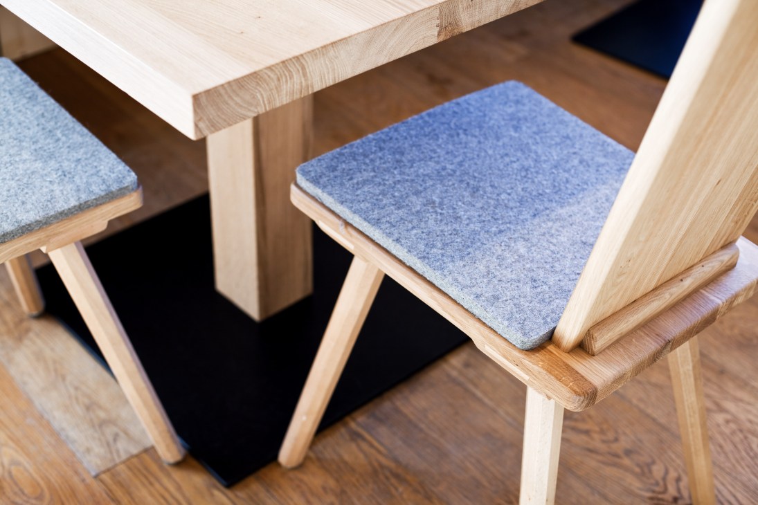 Wooden chairs with blue upholstered seats positioned at an oak table in the Oberholz mountain hut.