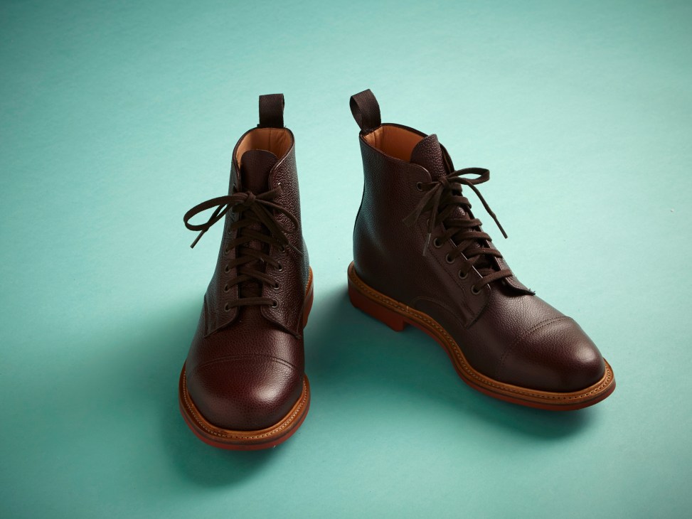 Pair of brown leather lace-up boots with tan soles against a turquoise background.