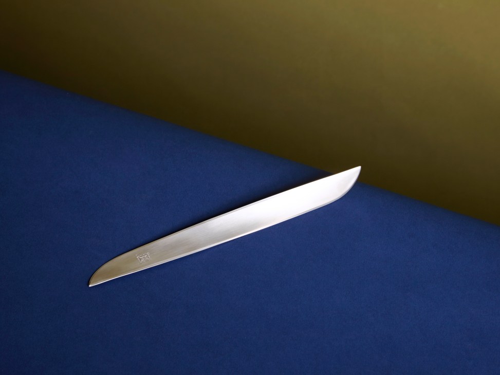 Ameland stainless steel letter opener by Enzo Mari for Danese on blue and olive background.