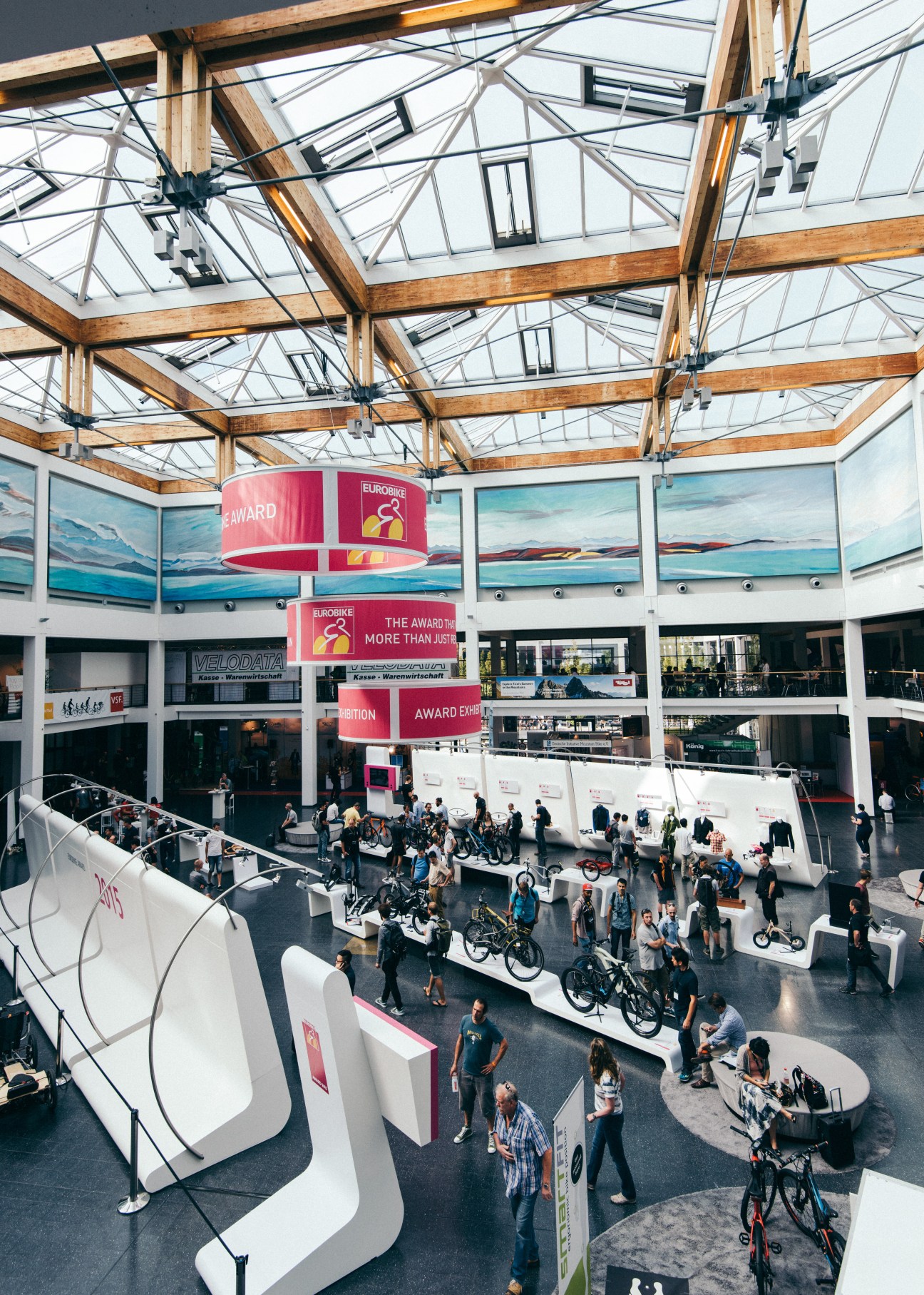 Aerial view of attendees gathered in the main hall of Eurobike trade fair with white exhibition stands and red award signage.