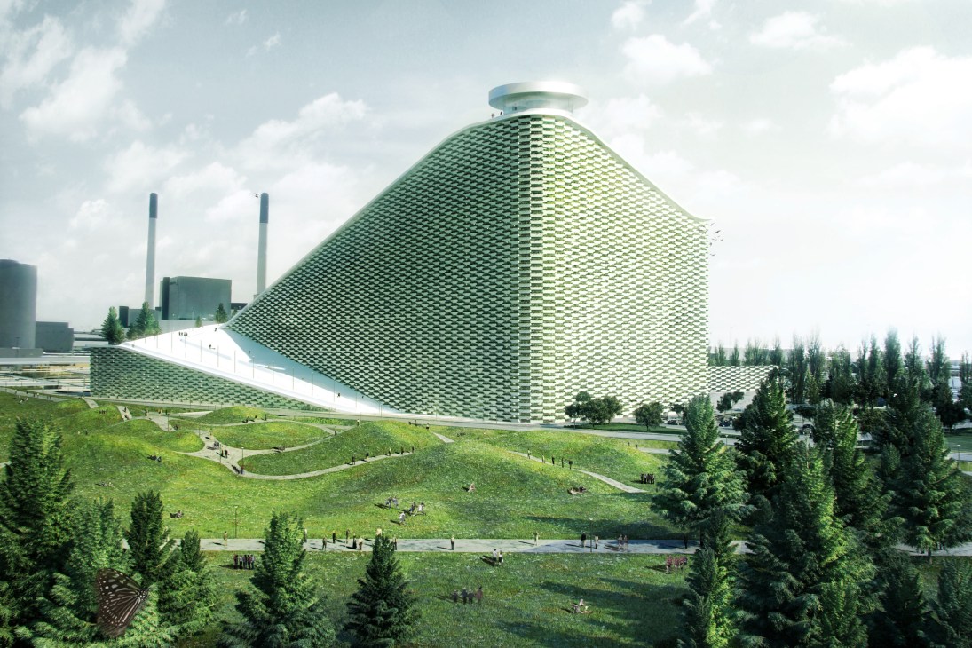 A large architectural structure with a distinctive green and white patterned facade designed like a ski slope, with grass and pine trees in the foreground.