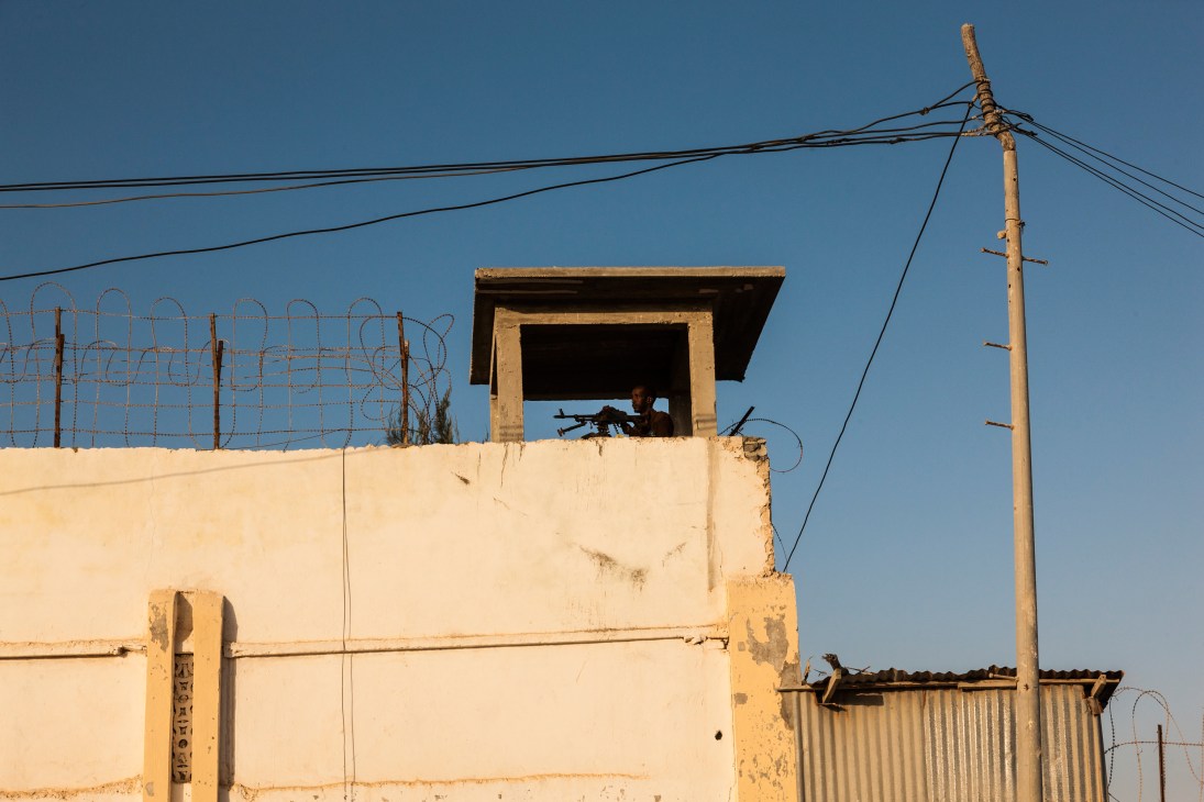 Armed guard in watchtower overlooking street with barbed wire fencing in Mogadishu
