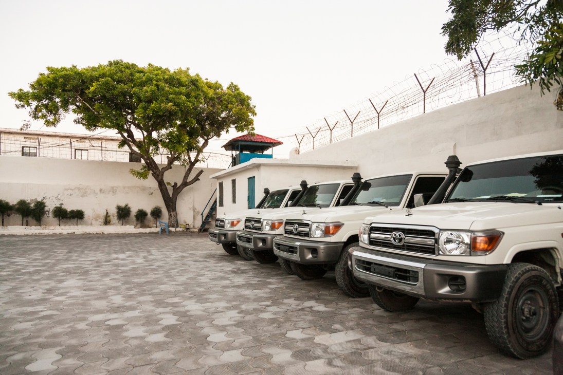 White Toyota Land Cruisers parked in a secure compound with high fencing and a guard tower at Peace Hotel Mogadishu.